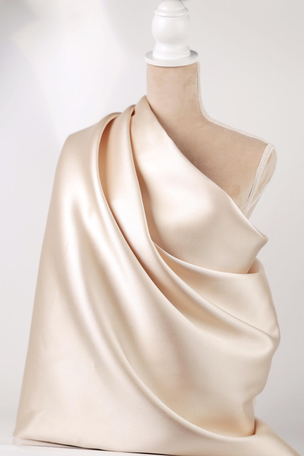 A mannequin wearing a beige satin fabric draped over its body.
