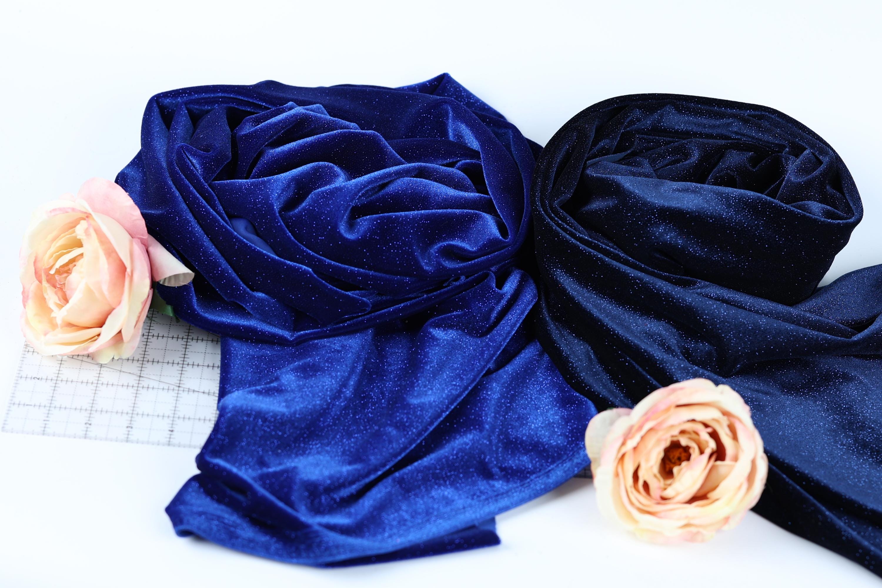 a close-up view of two fabric swatches, one blue and one black, with delicate pink roses resting on top of them.