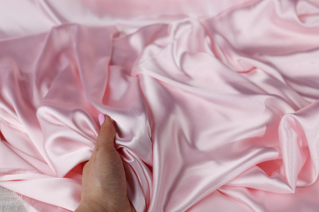 a person's hand on a pink fabric