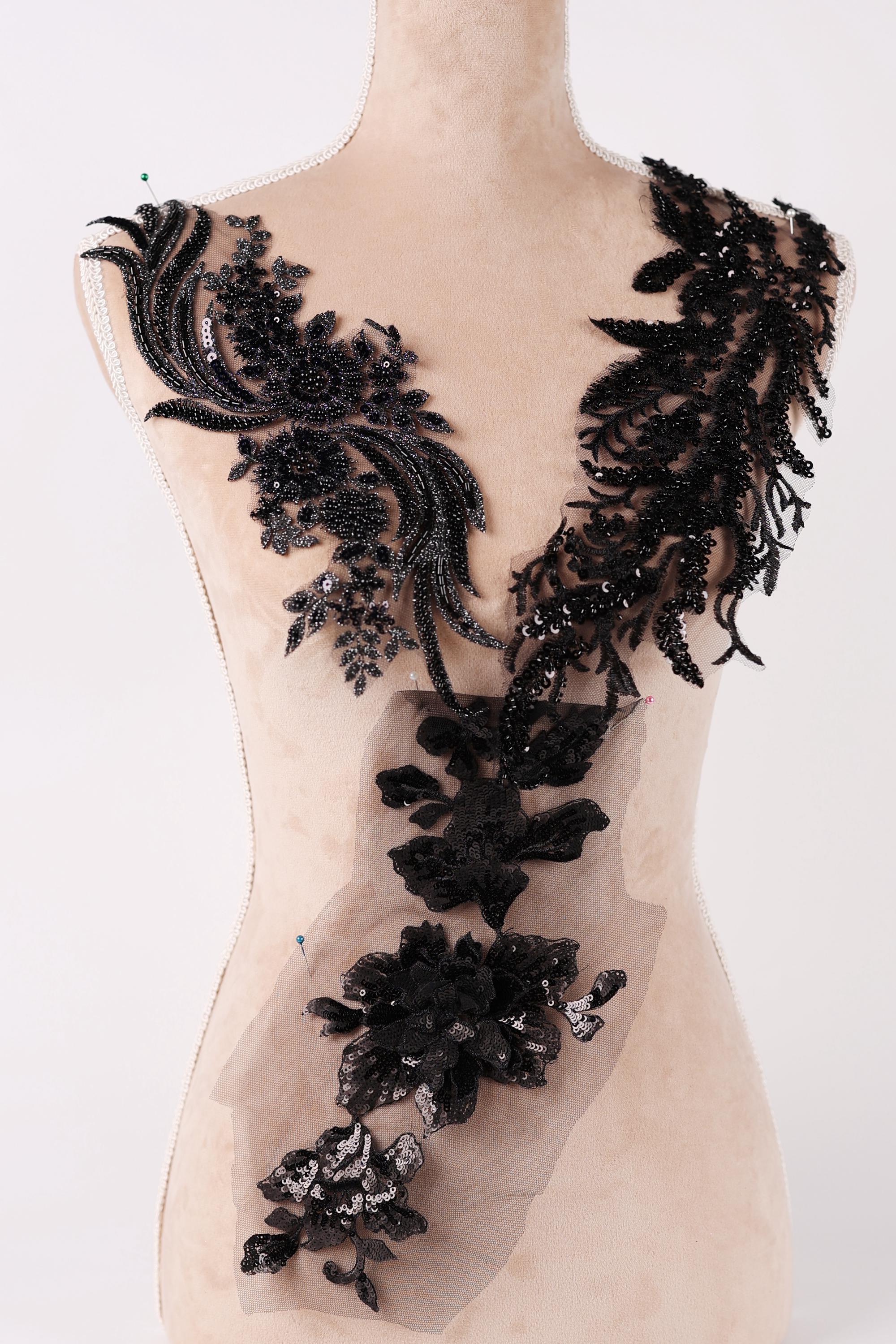 A mannequin wearing a dress with intricate black lace and floral embellishments.