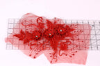 a red floral design with intricate details, including red flowers and red beads, placed on a transparent surface.