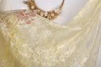 a close-up view of a delicate, yellow fabric with a floral pattern. The fabric appears to be made of sheer material, with a delicate and intricate design. The background is plain white, which allows the fabric to stand out prominently.
