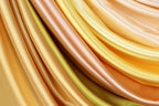 a close-up view of a variety of colorful, flowing fabrics, including yellow, orange, and green, arranged in a visually appealing manner.