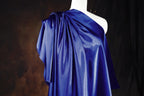 A mannequin wearing a blue one-shoulder dress with a draped, flowing fabric.