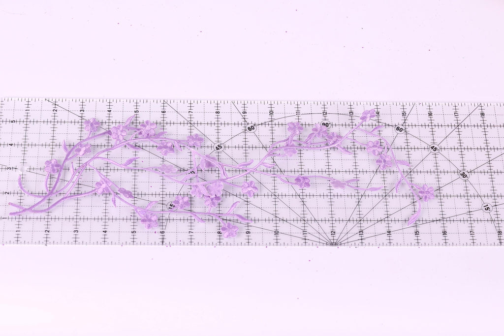 a clear ruler with a floral pattern of purple flowers placed on it.