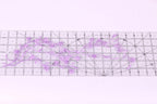 a clear ruler with a floral pattern of purple flowers placed on it.