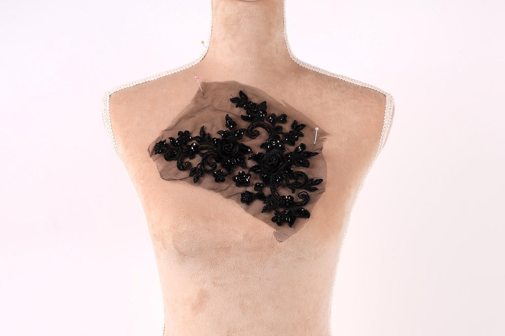 A mannequin with a black lace or beaded fabric piece attached to its chest.