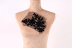 A mannequin with a black lace or beaded fabric piece attached to its chest.