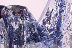 a close-up view of a fabric with a vibrant, multicolored pattern, including shades of blue, purple, and silver. The fabric appears to be made of sequins or other embellishments, creating a visually striking and intricate design.