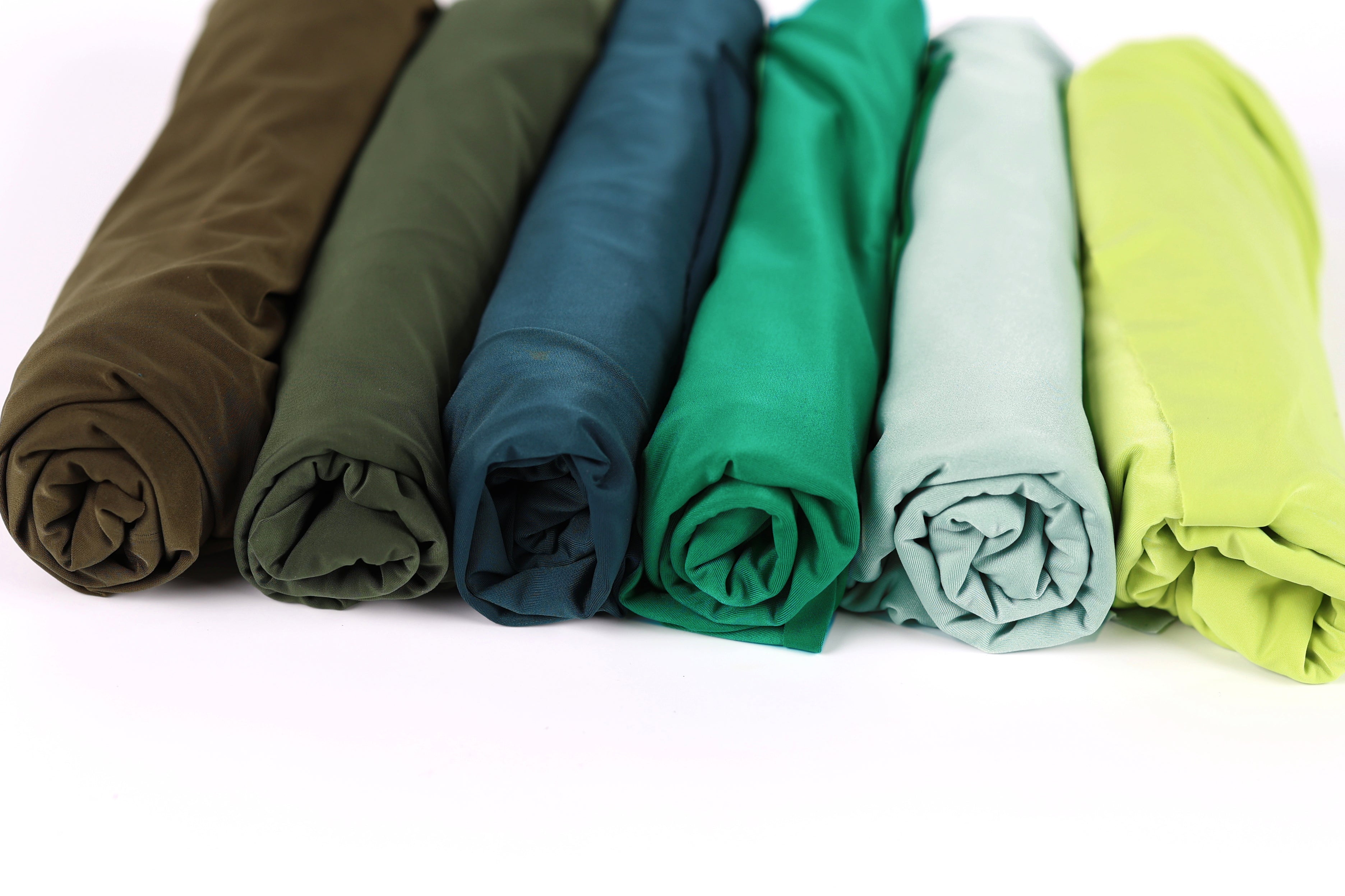 A row of six rolled-up fabric pieces in various colors, including green, blue, and yellow.