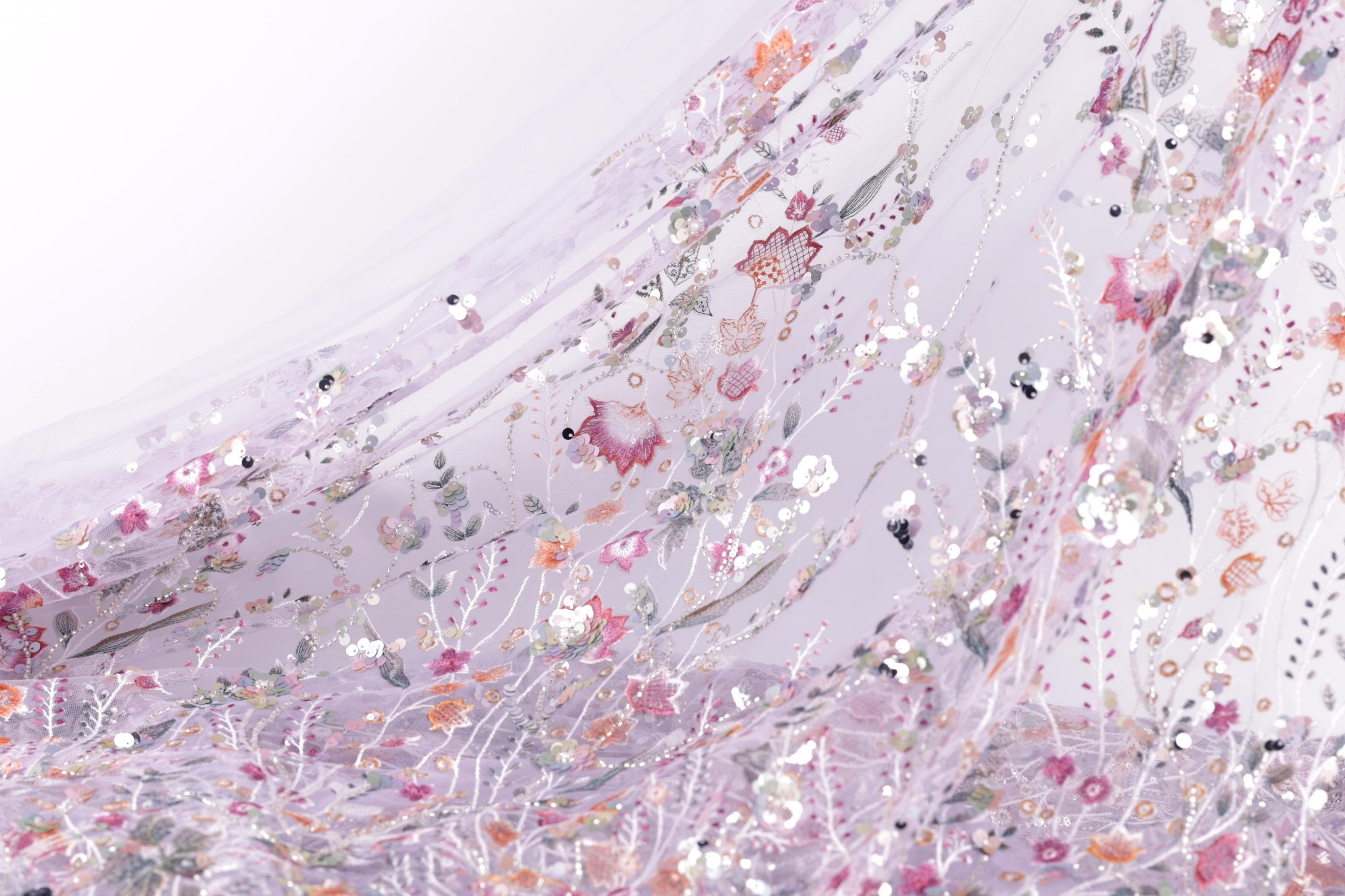 The image is a close-up view of a fabric with a floral pattern, featuring a variety of colorful flowers and leaves.