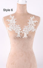 A mannequin wearing a beige dress with white lace appliques on the shoulders.