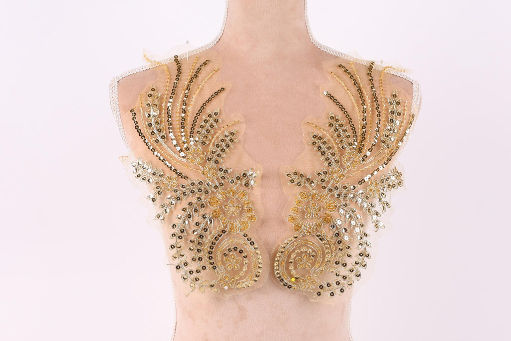 A mannequin torso with gold and beige sequined and beaded decorative pieces on the shoulders.