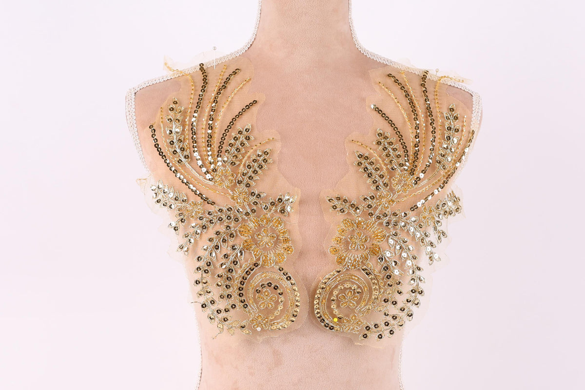 A mannequin torso with gold and beige sequined and beaded decorative pieces on the shoulders.