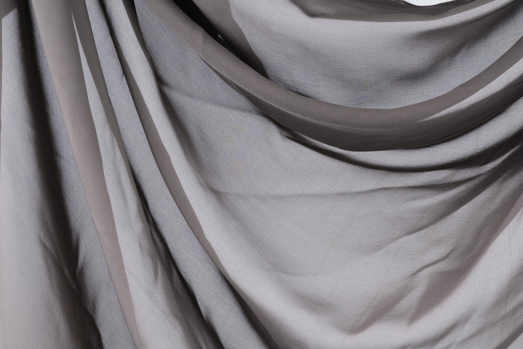 a close-up view of a gray fabric, possibly a sheer or sheer-like material, with a slightly wrinkled texture.