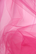 The image is a close-up of a pink fabric, possibly tulle, with a soft, flowing texture. The fabric appears to be slightly wrinkled, giving it a delicate and elegant appearance.