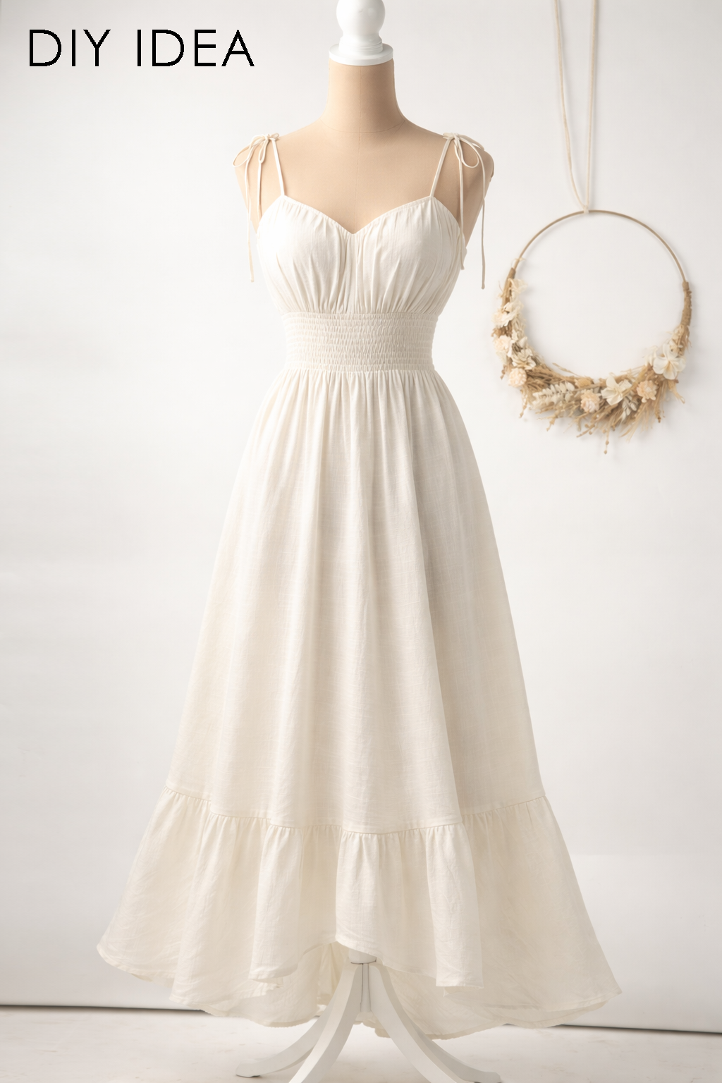 A white, ruffled dress displayed on a mannequin, with a wreath hanging on the wall behind it.