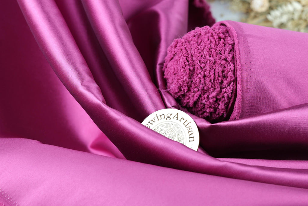 a close-up view of a fabric with a vibrant purple color, featuring a small circular object with text on it, placed on top of the fabric.