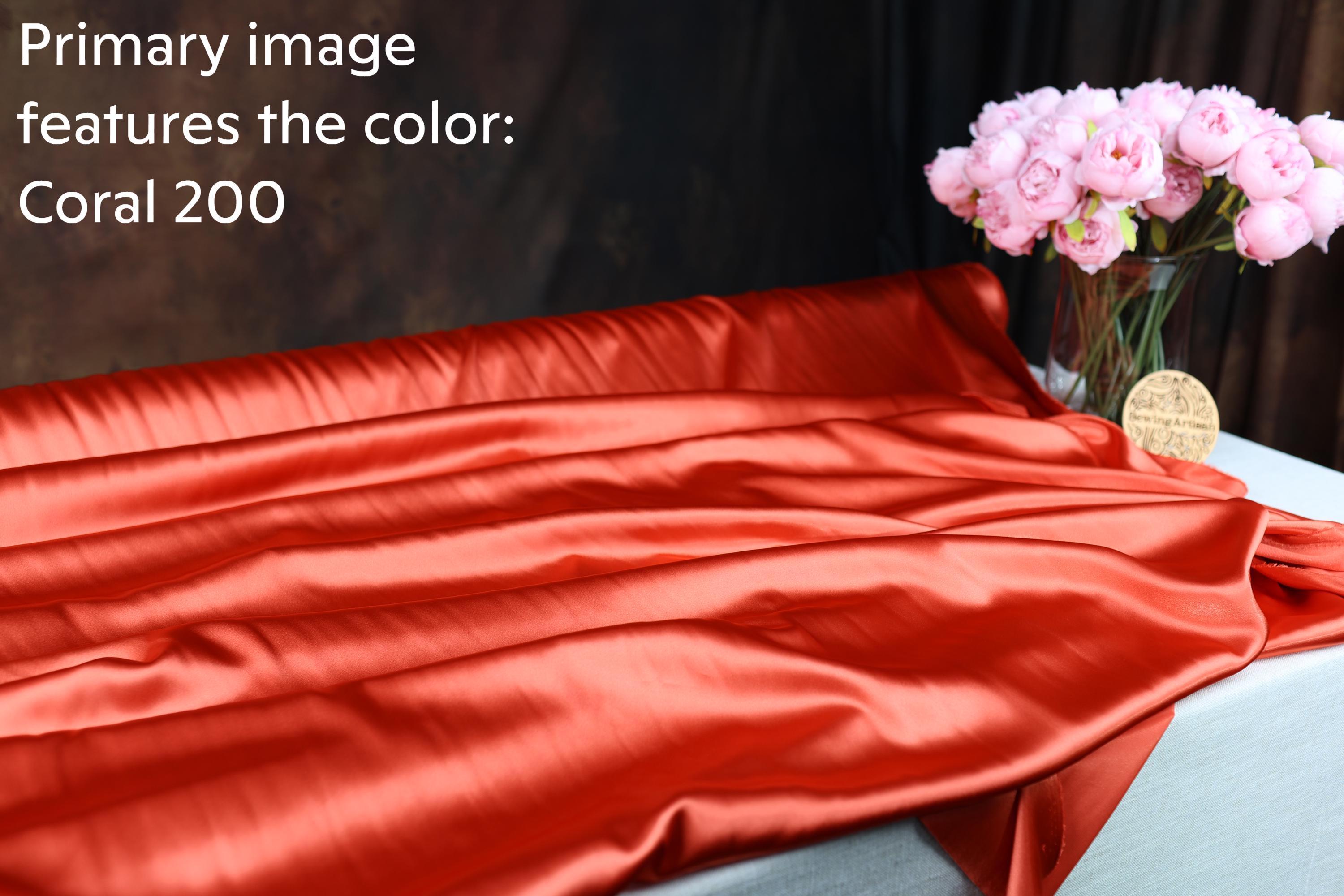 a vibrant red fabric with a floral arrangement of pink flowers in a glass vase placed on a table.