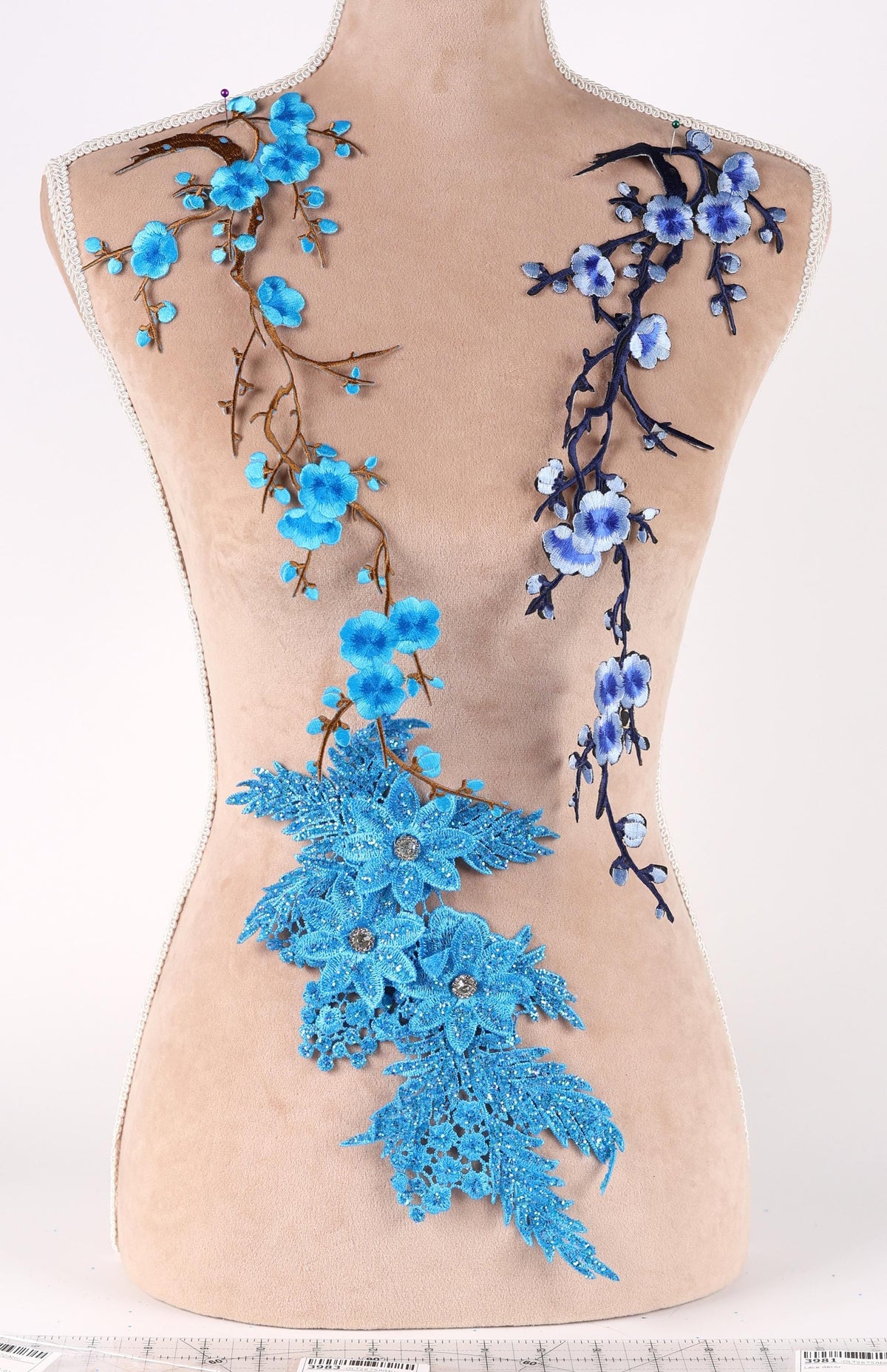A mannequin torso with blue floral designs on it, including blue flowers and branches.