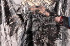A close-up view of a hand holding a piece of black and silver fabric with intricate beading and embroidery.