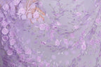 a close-up view of a fabric with a delicate floral pattern in shades of purple. The fabric appears to be made of sheer material, with numerous small purple flowers and leaves intricately woven into the fabric, creating a visually appealing and delicate design.
