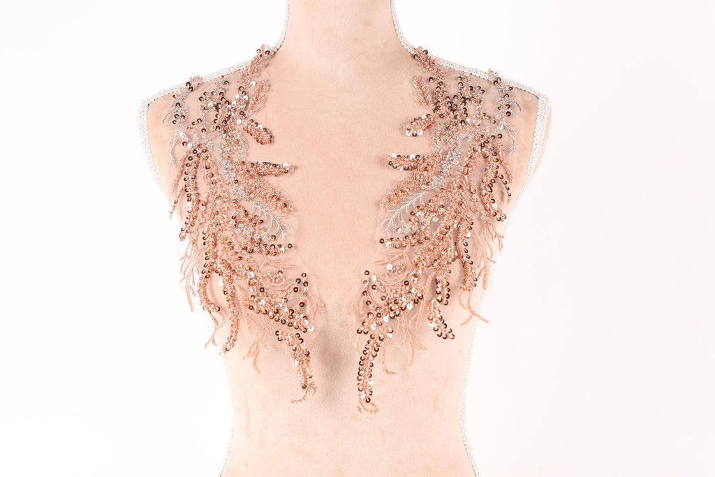 A mannequin wearing a necklace with intricate, shimmering, and delicate peach-colored sequin and feather-like embellishments.