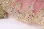 a close-up view of a delicate, pink and gold lace or fabric with intricate, ornate patterns and designs.