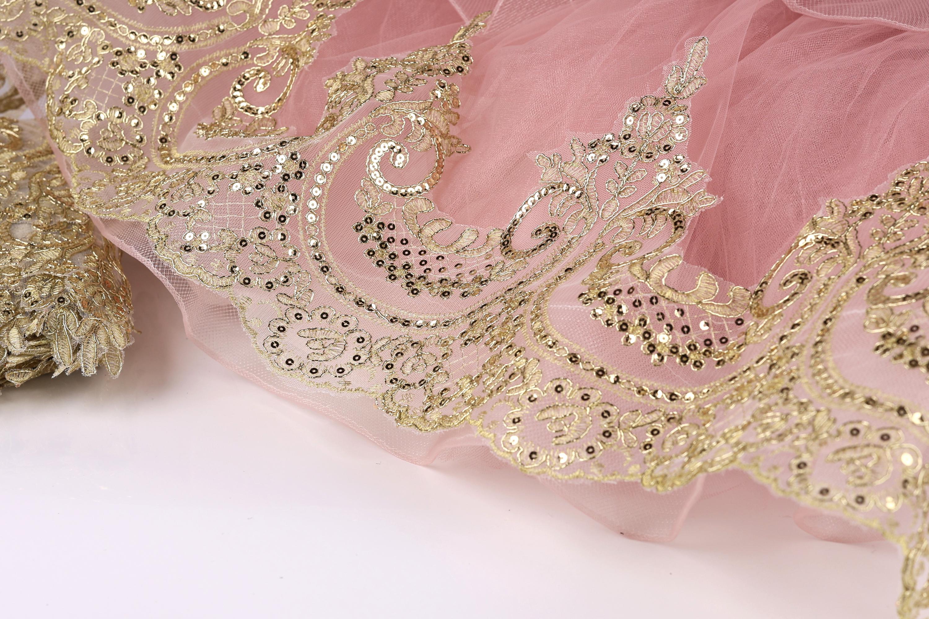 a close-up view of a delicate, pink and gold lace or fabric with intricate, ornate patterns and designs.