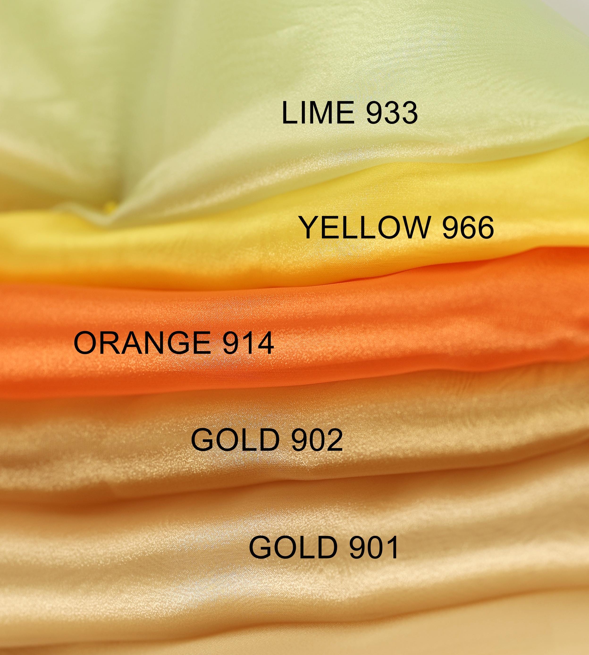 A close-up image of a stack of fabric swatches in various colors, including lime green, yellow, orange, gold, and gold.