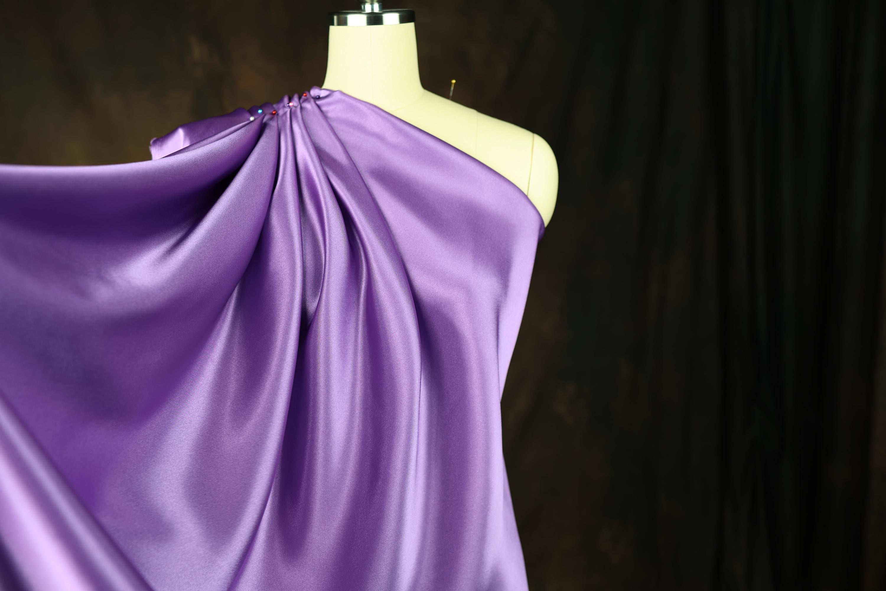 a dress on a mannequin with a purple cloth draped over it