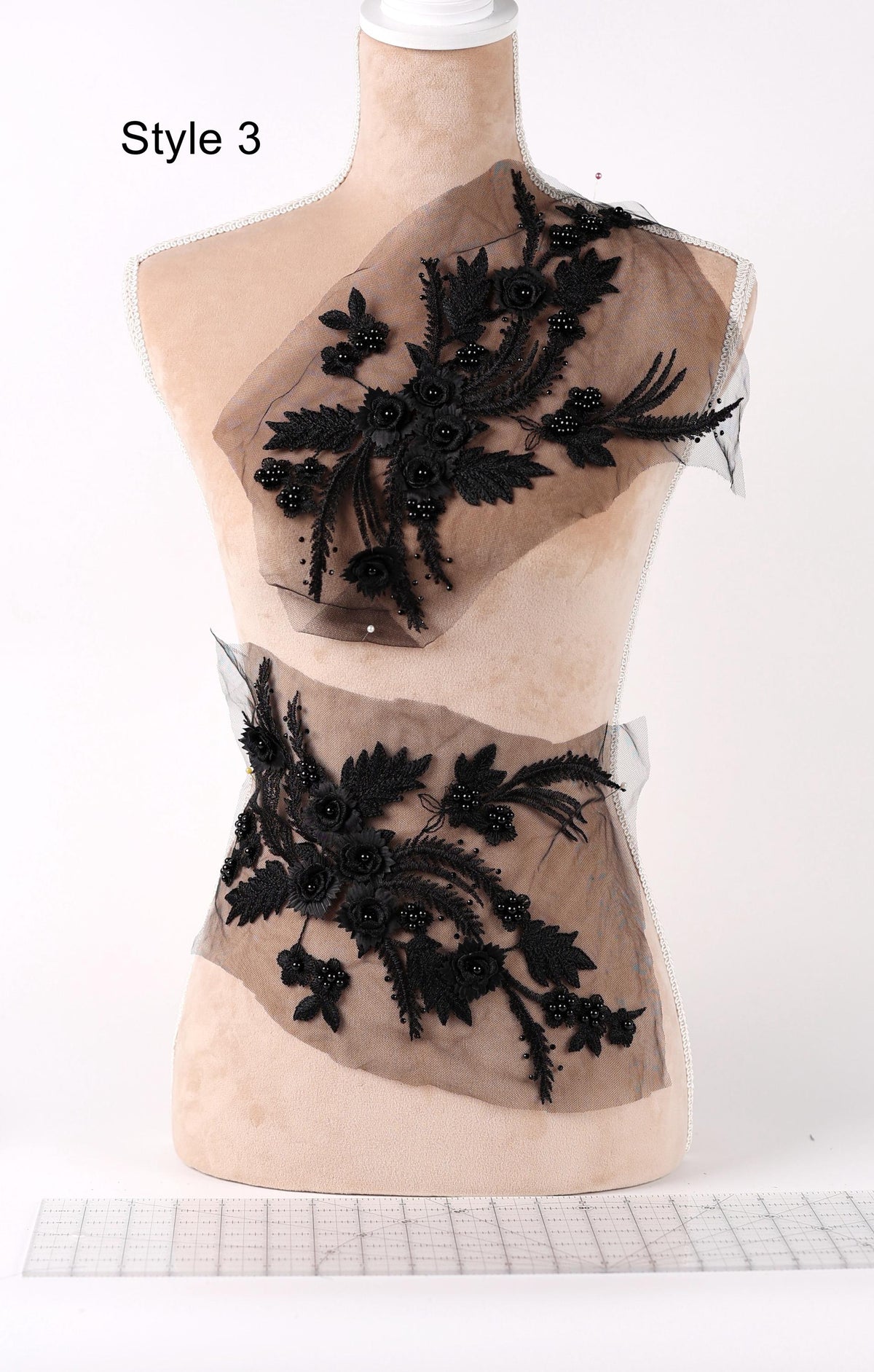 A mannequin wearing a dress with black floral embroidery and a beaded belt.
