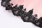 A close-up view of a delicate lace trim on a fabric, with a pink background.