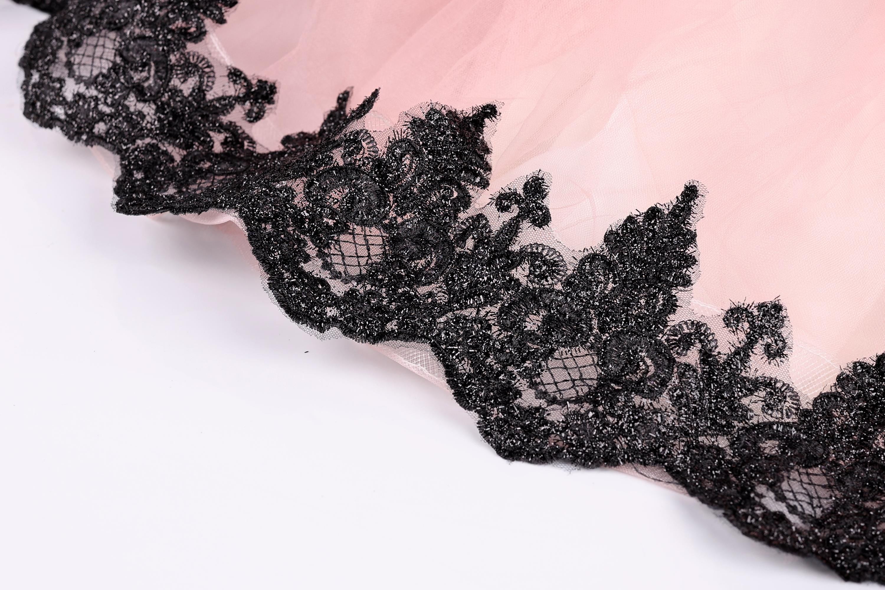 A close-up view of a delicate lace trim on a fabric, with a pink background.