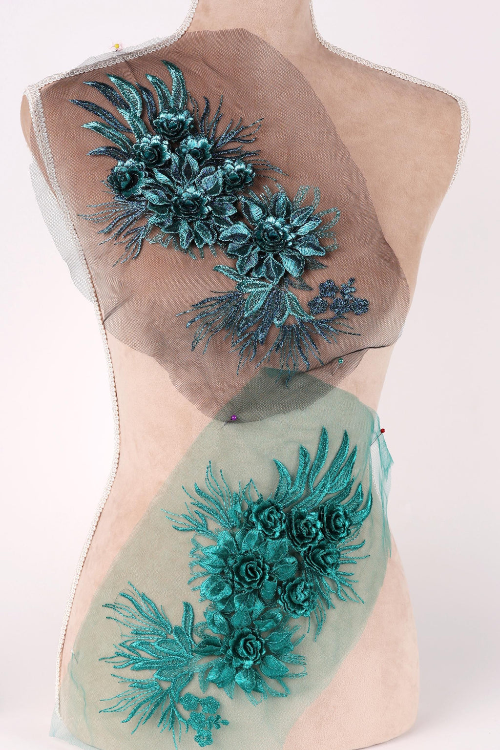 a mannequin with a back adorned with a decorative floral design in shades of blue and green. The design consists of various flowers and leaves, creating a visually appealing and intricate pattern.
