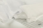a close-up view of a white fabric, possibly a sheer or sheer-like material, with a ruler or measuring tape placed on top of it.