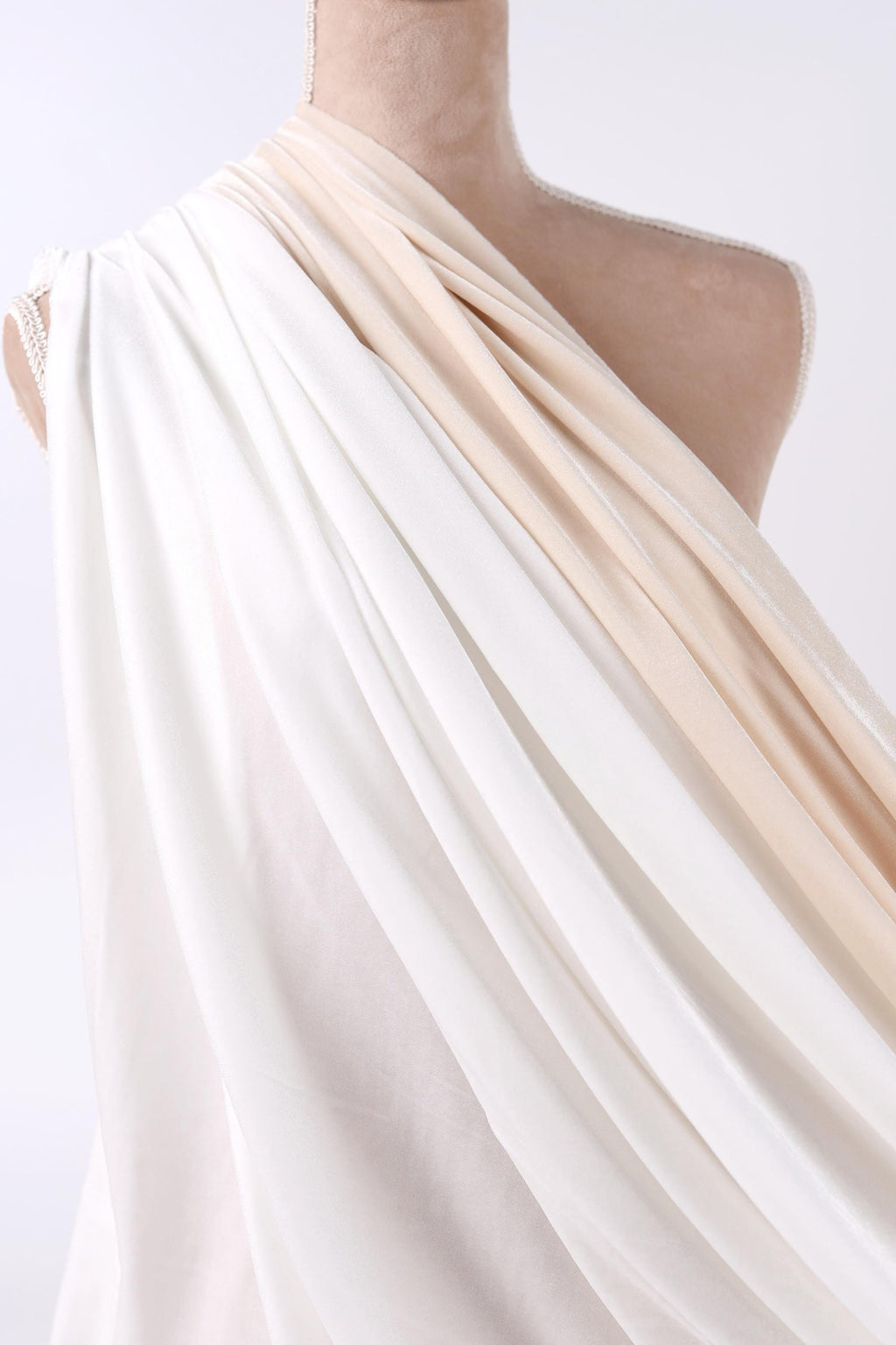 A mannequin wearing a flowing white and beige draped garment.