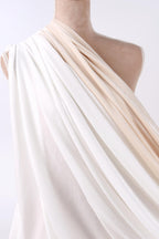 A mannequin wearing a flowing white and beige draped garment.