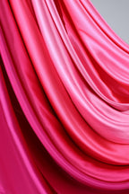 a close-up view of a vibrant pink fabric, with its folds and creases creating a dynamic and visually striking pattern.
