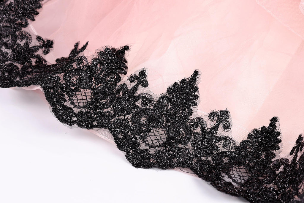 A close-up view of a delicate, lace-like fabric with a pink background.