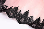 A close-up view of a delicate, lace-like fabric with a pink background.
