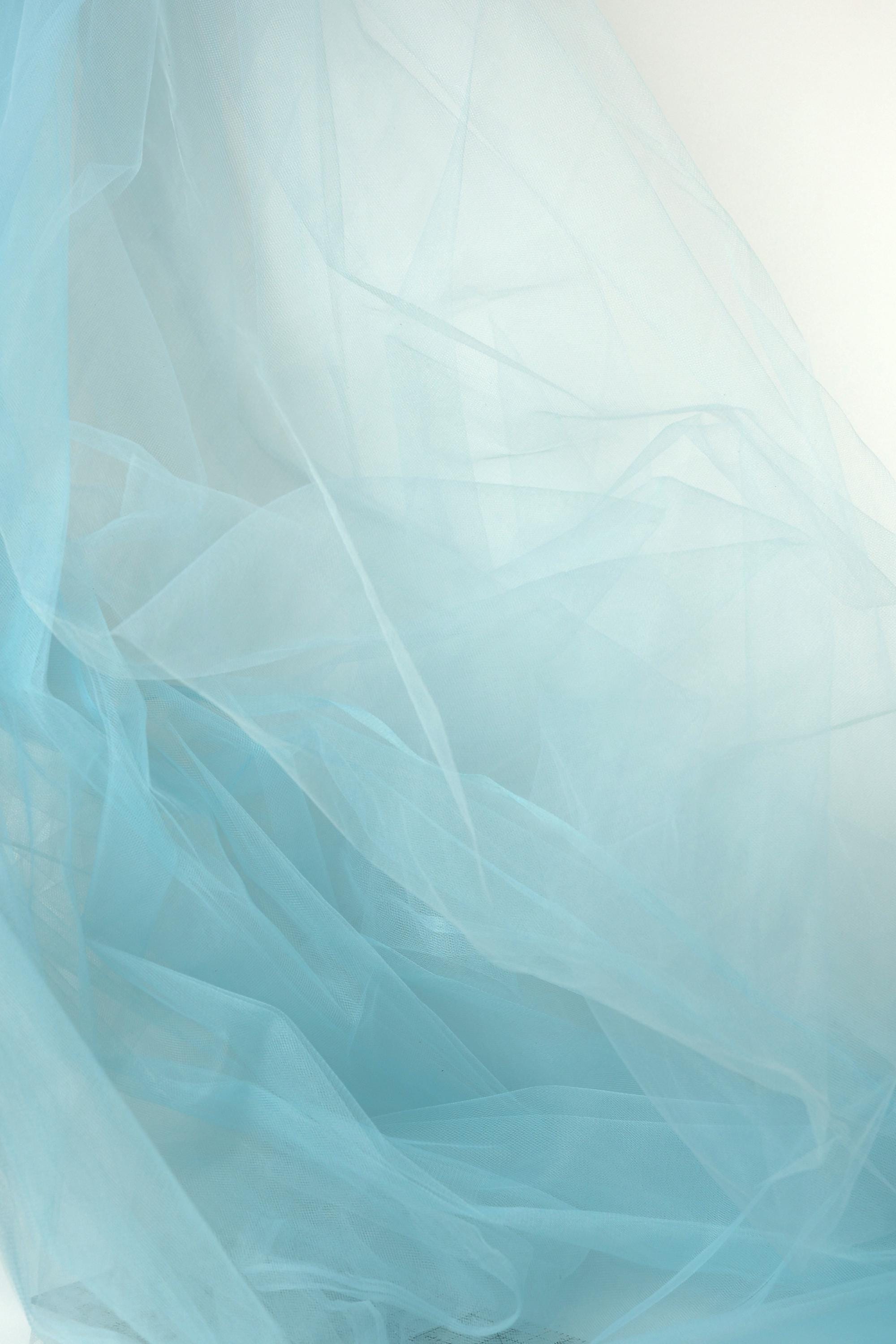 The image is a close-up of a light blue, sheer fabric, with its delicate and flowing texture.
