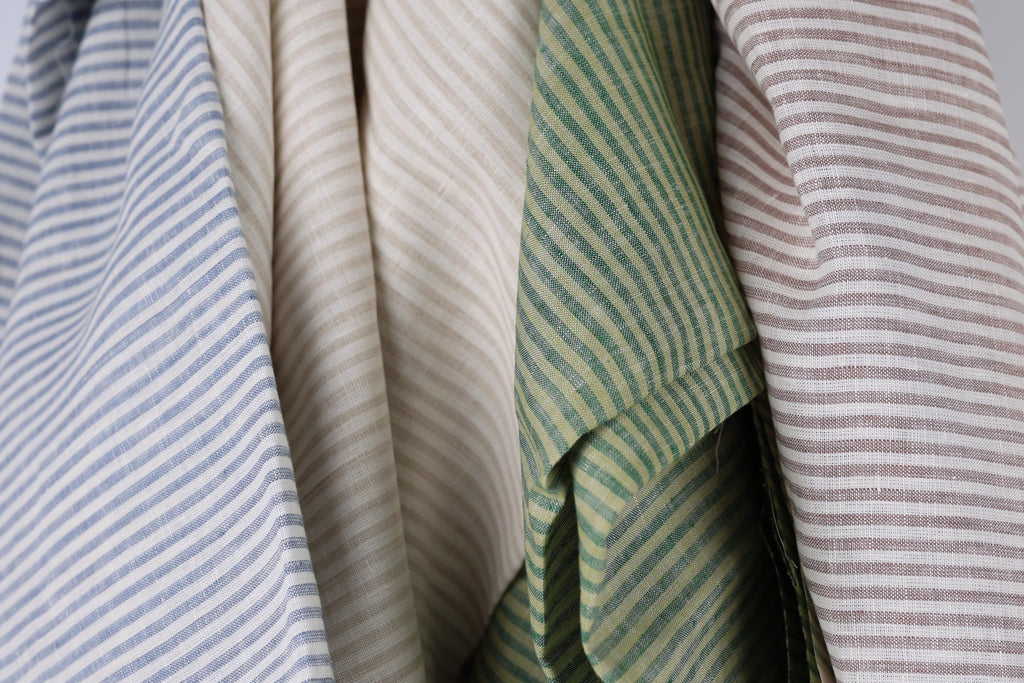 a close-up view of several fabric swatches with different striped patterns, including blue, beige, green, and brown stripes.