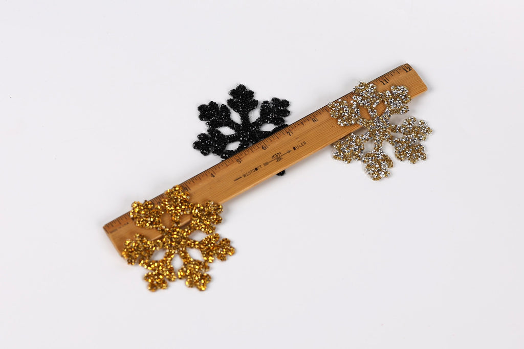 a wooden ruler with three snowflake-shaped decorations placed on it.