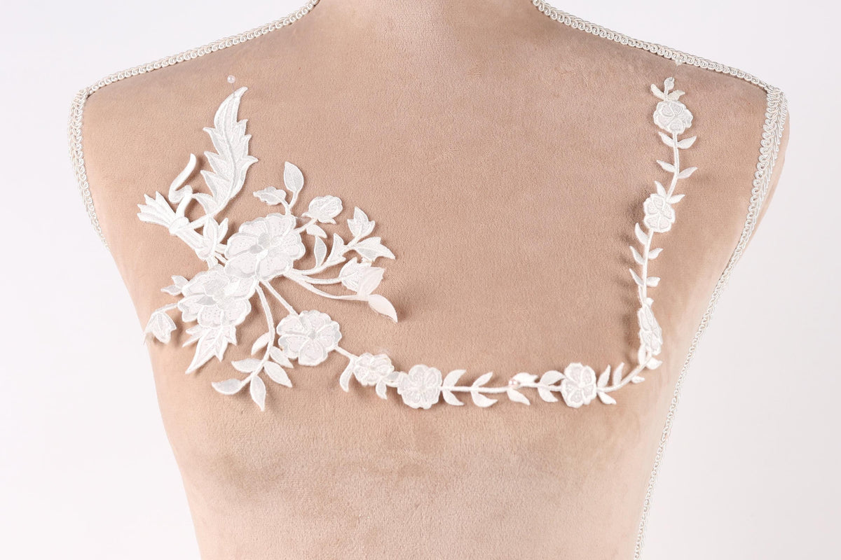A mannequin torso with a delicate white lace design on the bust area, featuring a floral pattern.