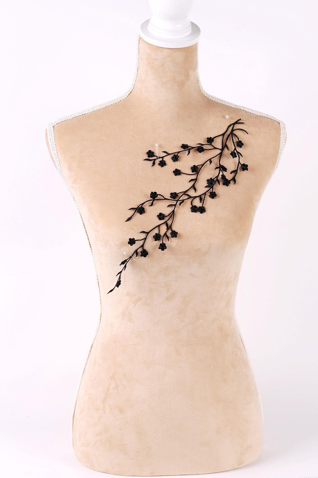 A mannequin with a beige body and a black branch design on its chest.