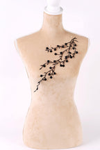 A mannequin with a beige body and a black branch design on its chest.