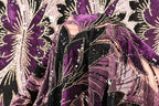 a close-up view of a fabric with a vibrant purple and black pattern, adorned with sequins and beads. The fabric appears to be a piece of clothing or textile, with the intricate design and embellishments making it visually striking.