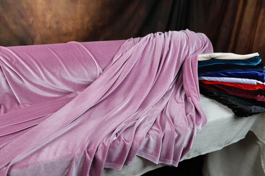 a bed covered in a purple blanket next to a pile of blankets