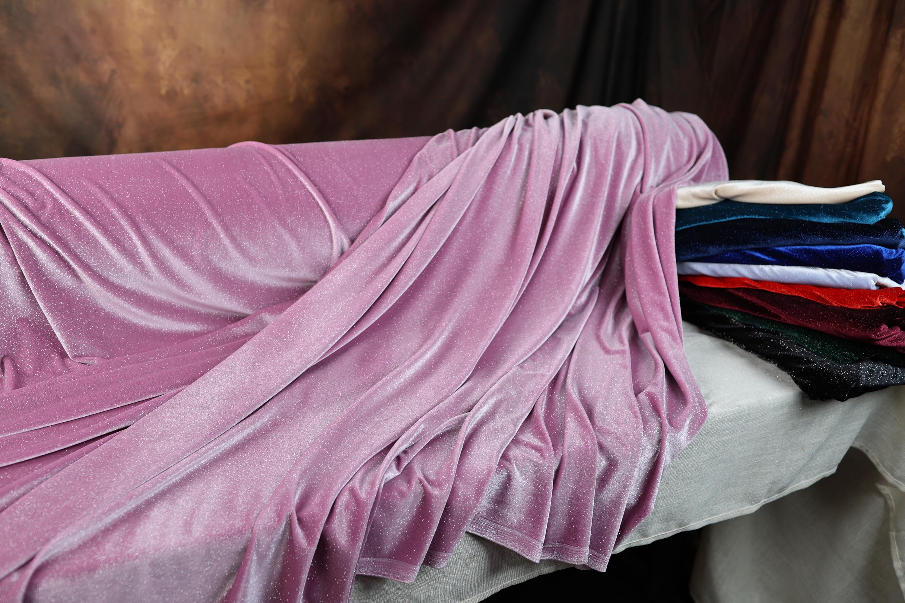 a bed covered in a purple blanket next to a pile of blankets